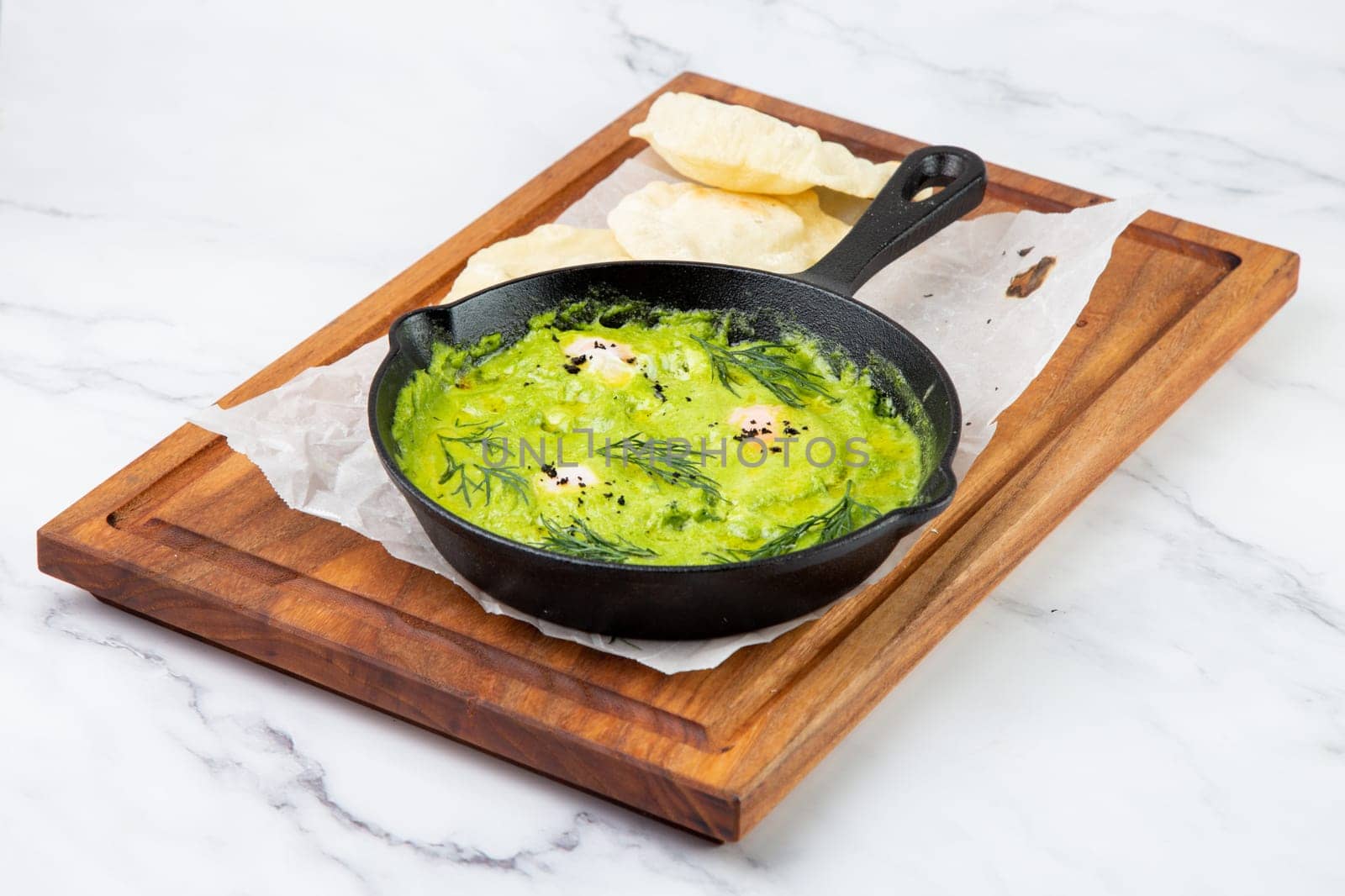 broccoli cream soup with herbs, cheese and tortillas in a frying pan, top view by tewolf