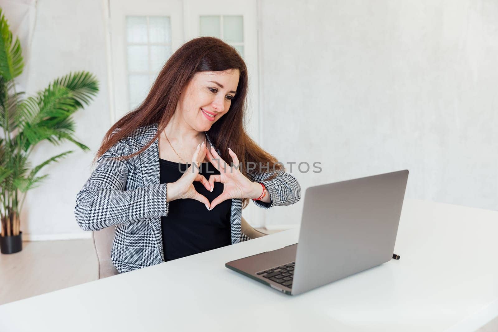 Happy woman showing her hands at heart in office