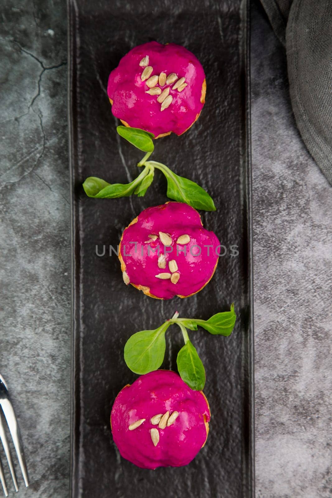 dessert of baked buns with raspberry topping and seed decorations