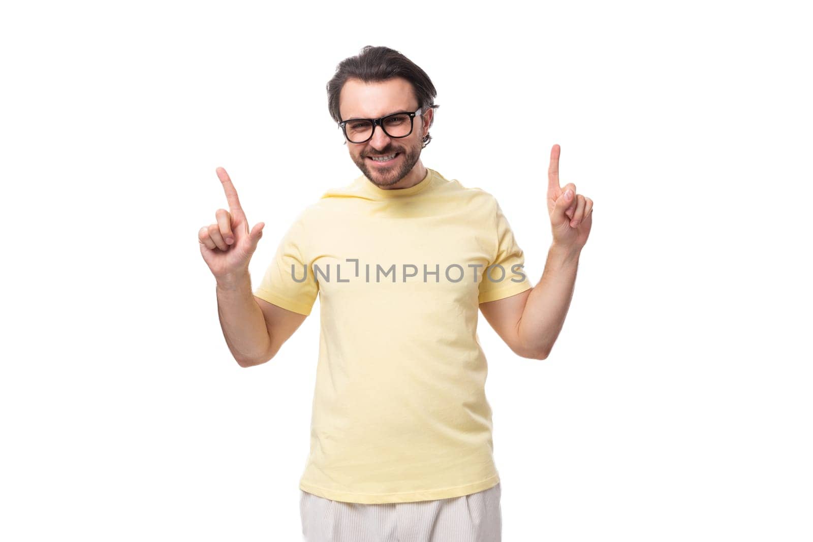 young brunette man in a t-shirt and glasses tells the news on a white background with copy space by TRMK