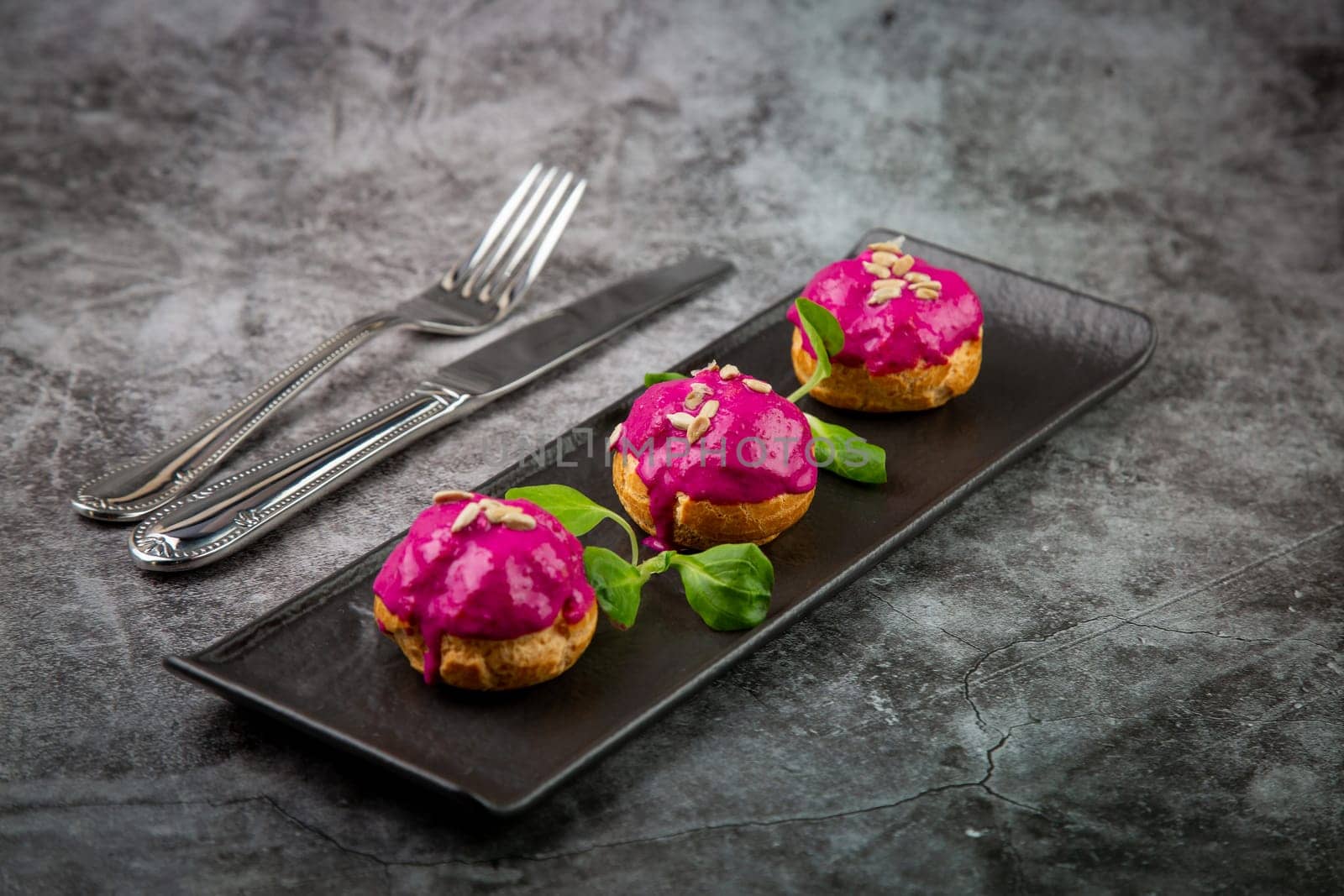 dessert of baked buns with raspberry topping and seed decorations