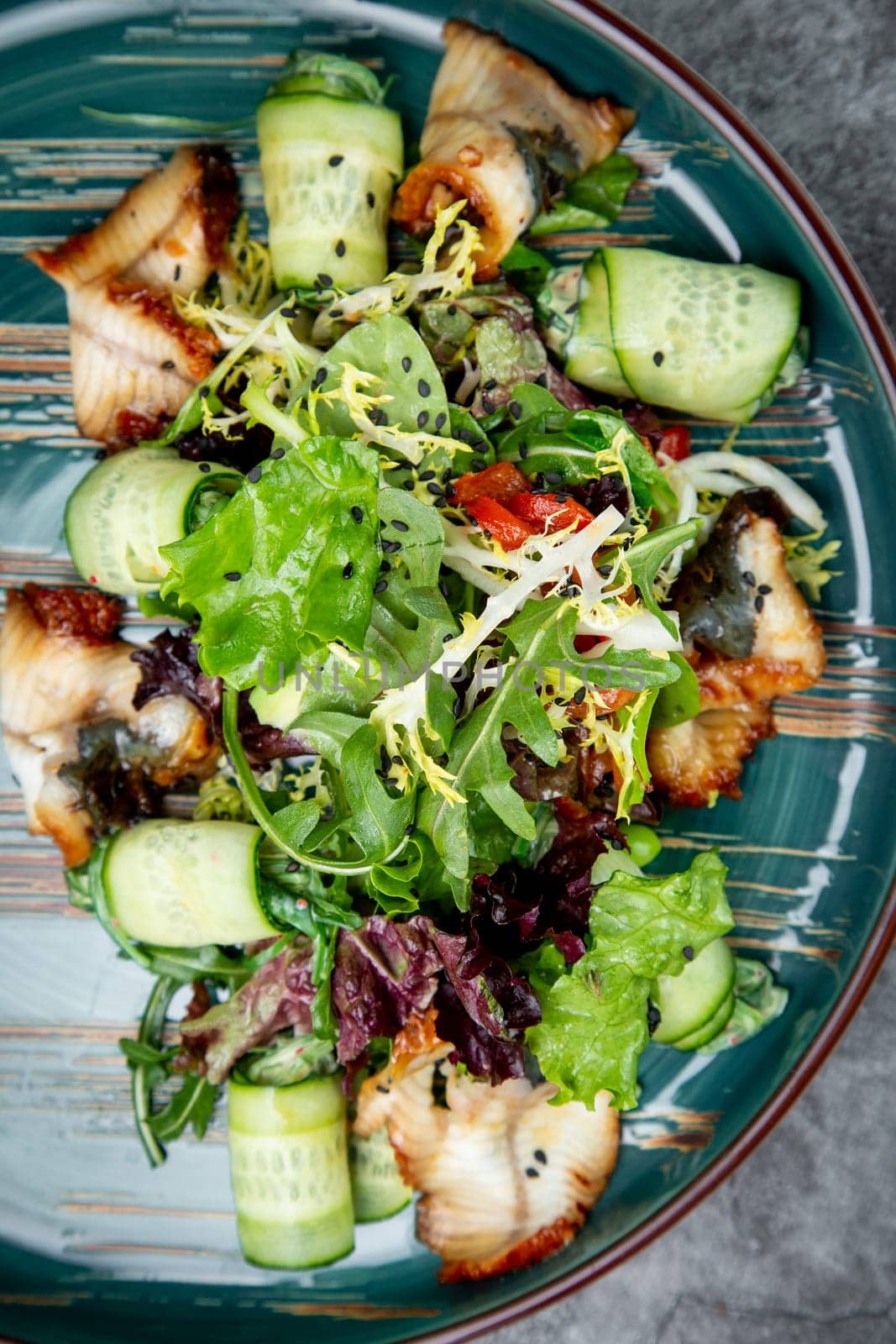 salad with arugula, lettuce, cucumber rolls, fish and sesame seeds, top view by tewolf