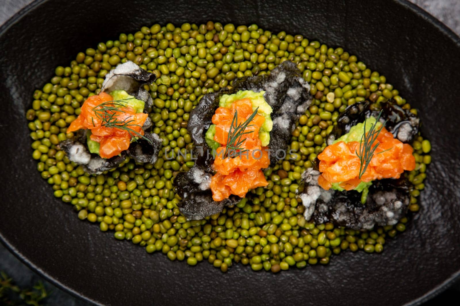 black caviar, red fish and wassabi on a plate with peas