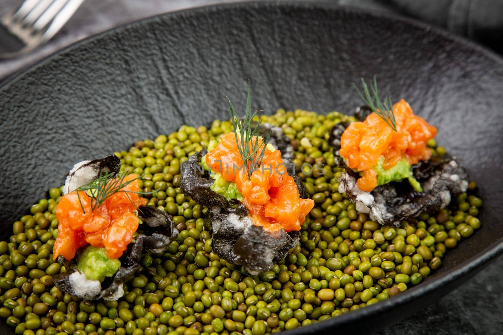 black caviar, red fish and wassabi on a plate with peas