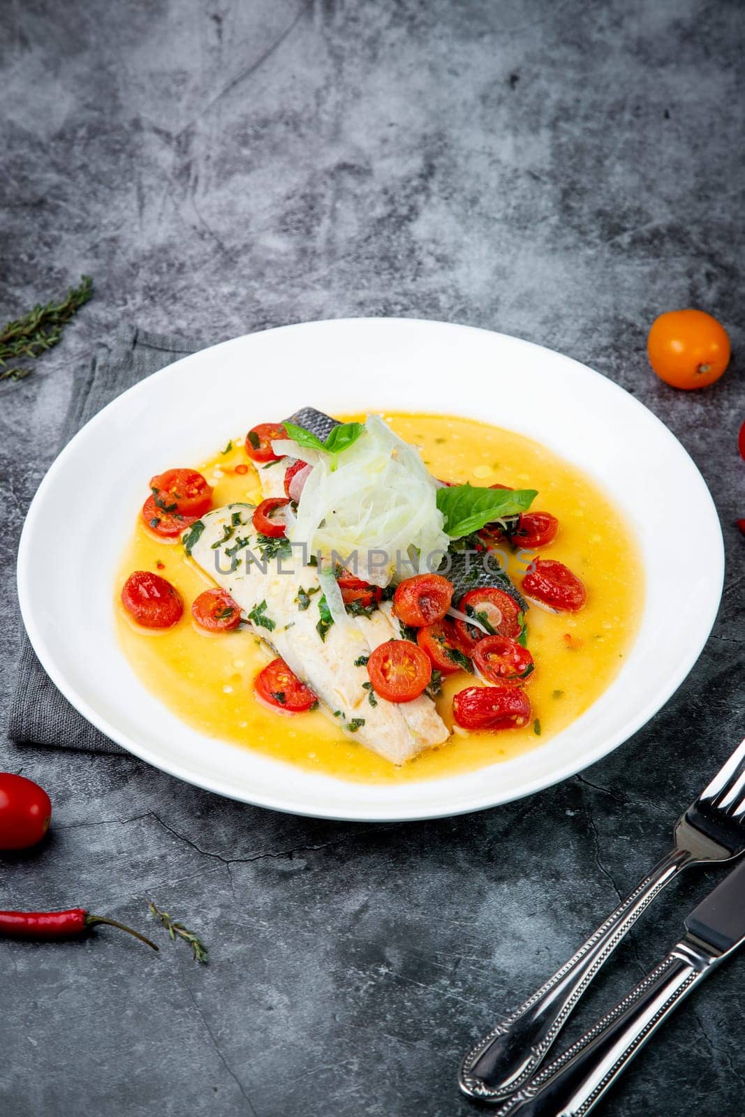 unpeeled fish with gravy, herbs, cherry tomatoes and onions, top view by tewolf