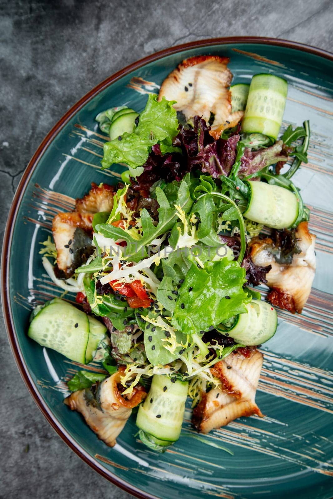 salad with arugula, lettuce, cucumber rolls, fish and sesame seeds, top view by tewolf