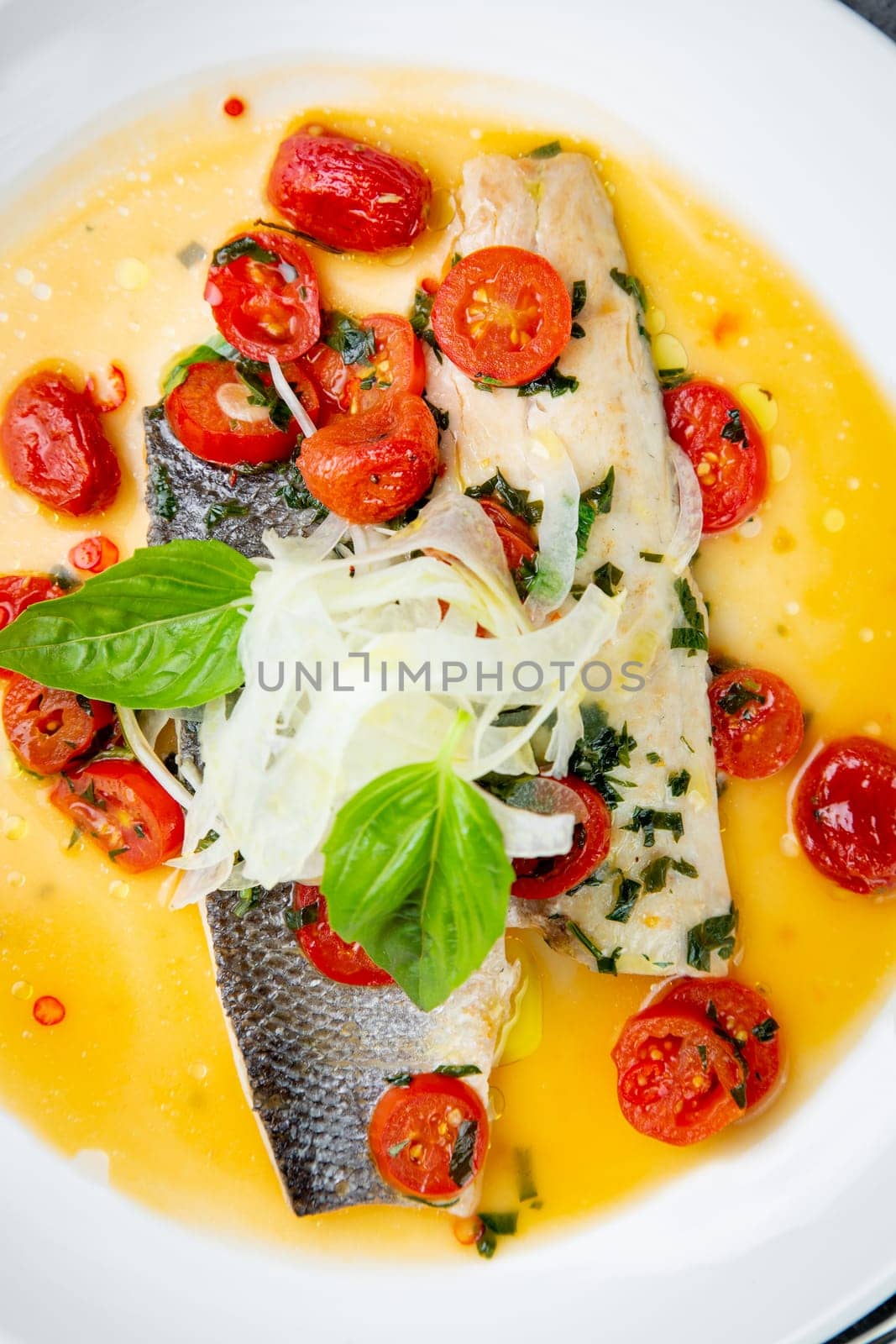 unpeeled fish with gravy, herbs, cherry tomatoes and onions, top view by tewolf