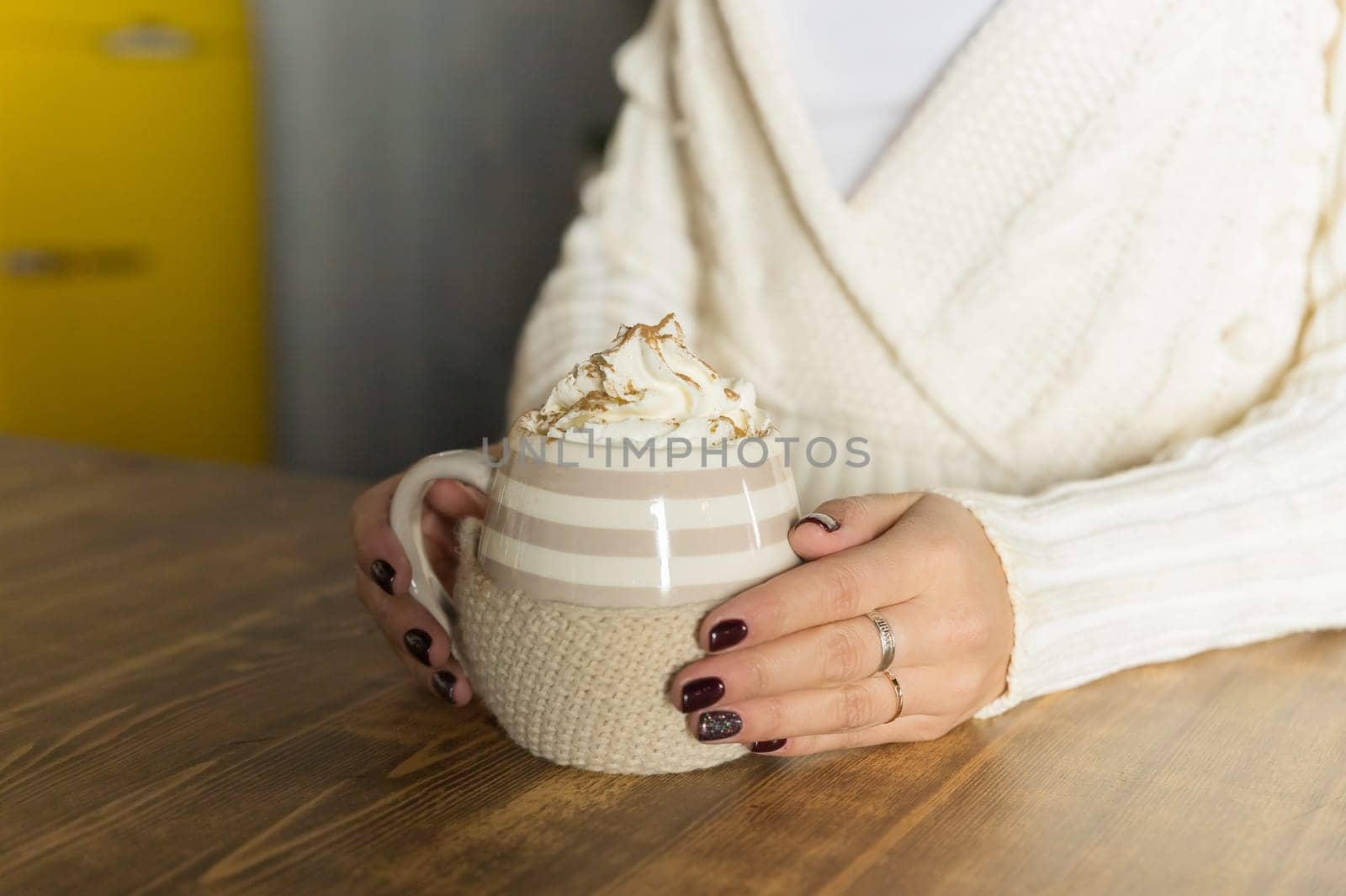 Morning coffee with whipped cream and marshmallows. Autumn composition. Hand with a cup. Composition with light cups and glass sugar bowl.