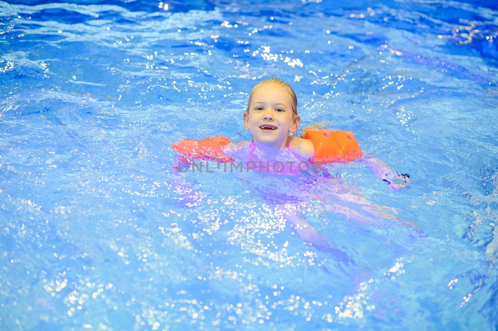 Cute girl with inflatables swimming in the pool. Healthy sport for children by Lobachad