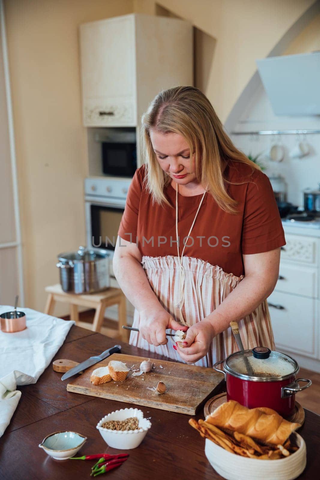 Female housewife prepares delicious food in kitchen from products by Simakov