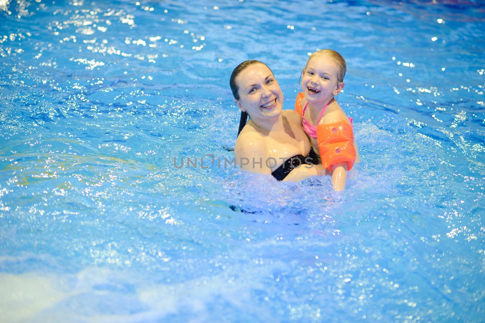 Mom and daughter are swimming in the pool with an inflatable. Healthy sports for the family.