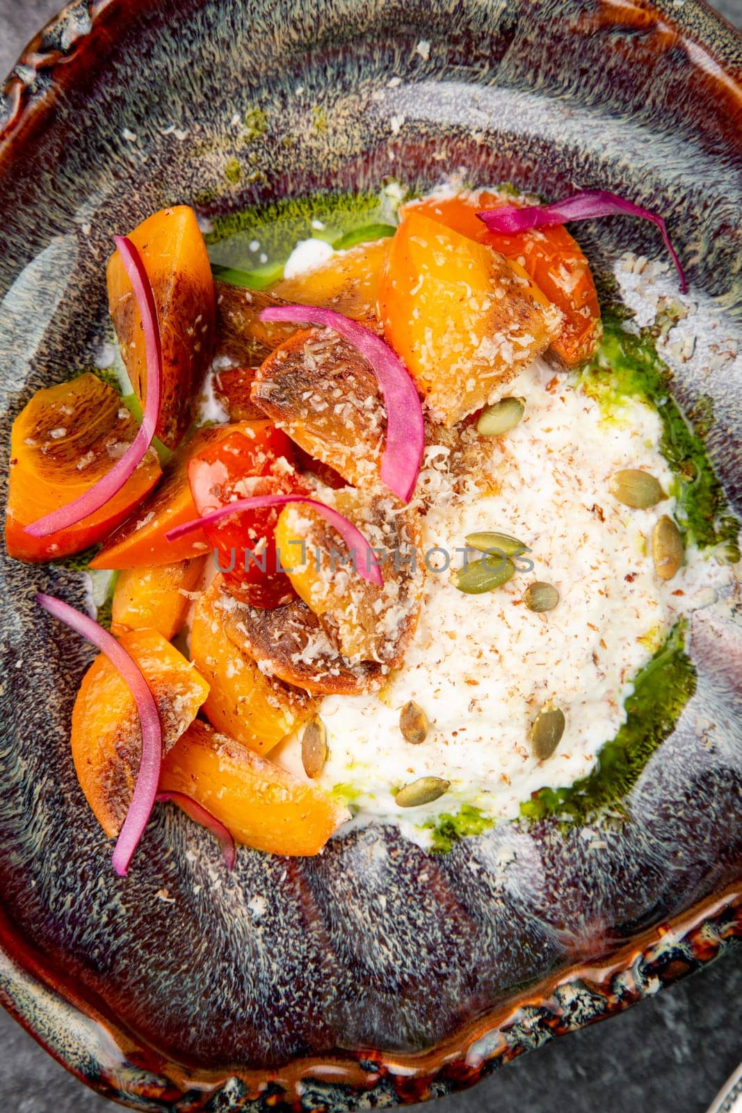 side view of a dish of baked persimmons, colored peppers, rice and seeds by tewolf