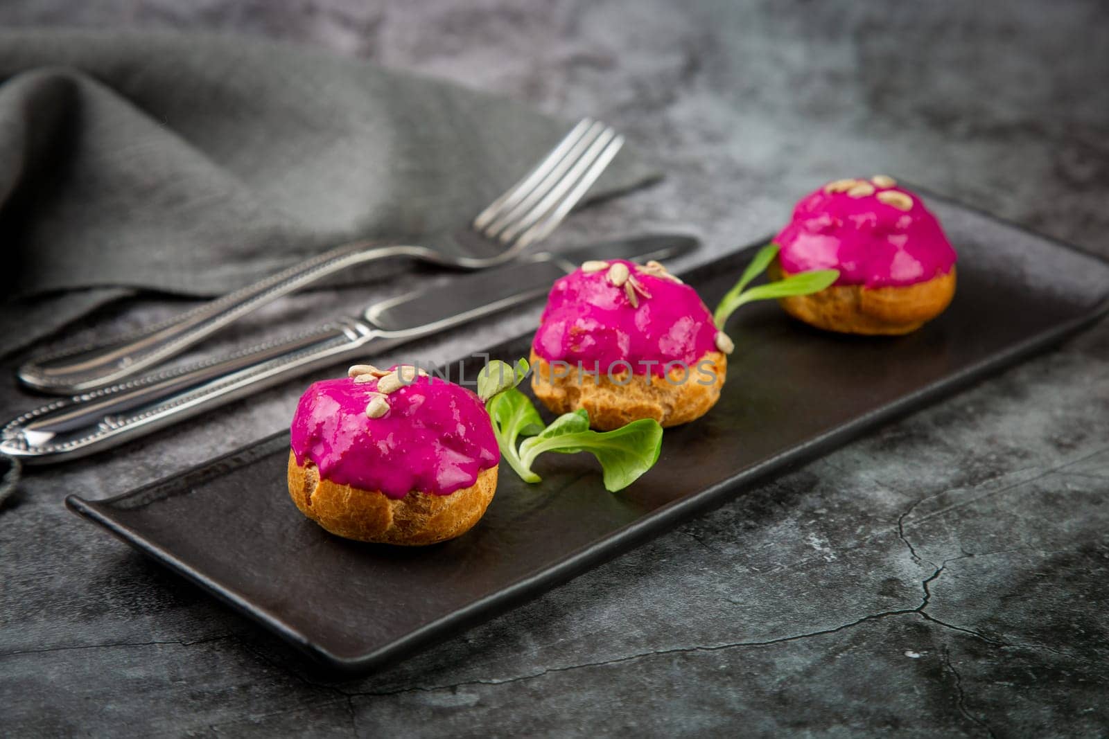 dessert of baked buns with raspberry topping and seed decorations