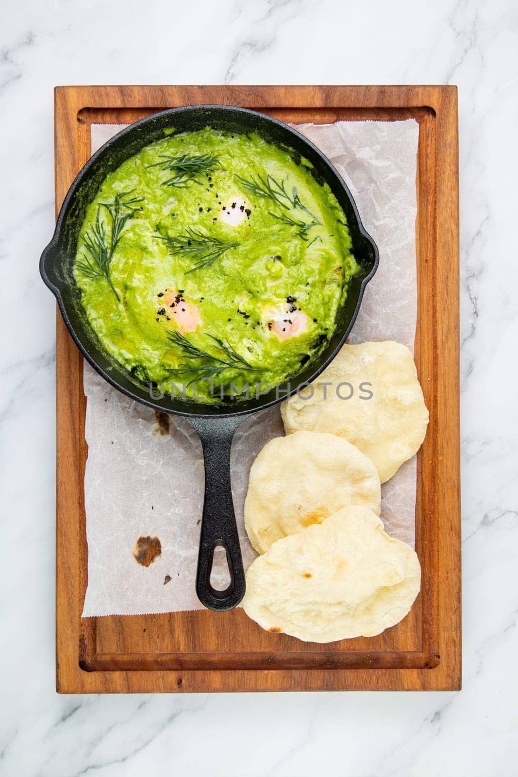 broccoli cream soup with herbs, cheese and tortillas in a frying pan, top view by tewolf