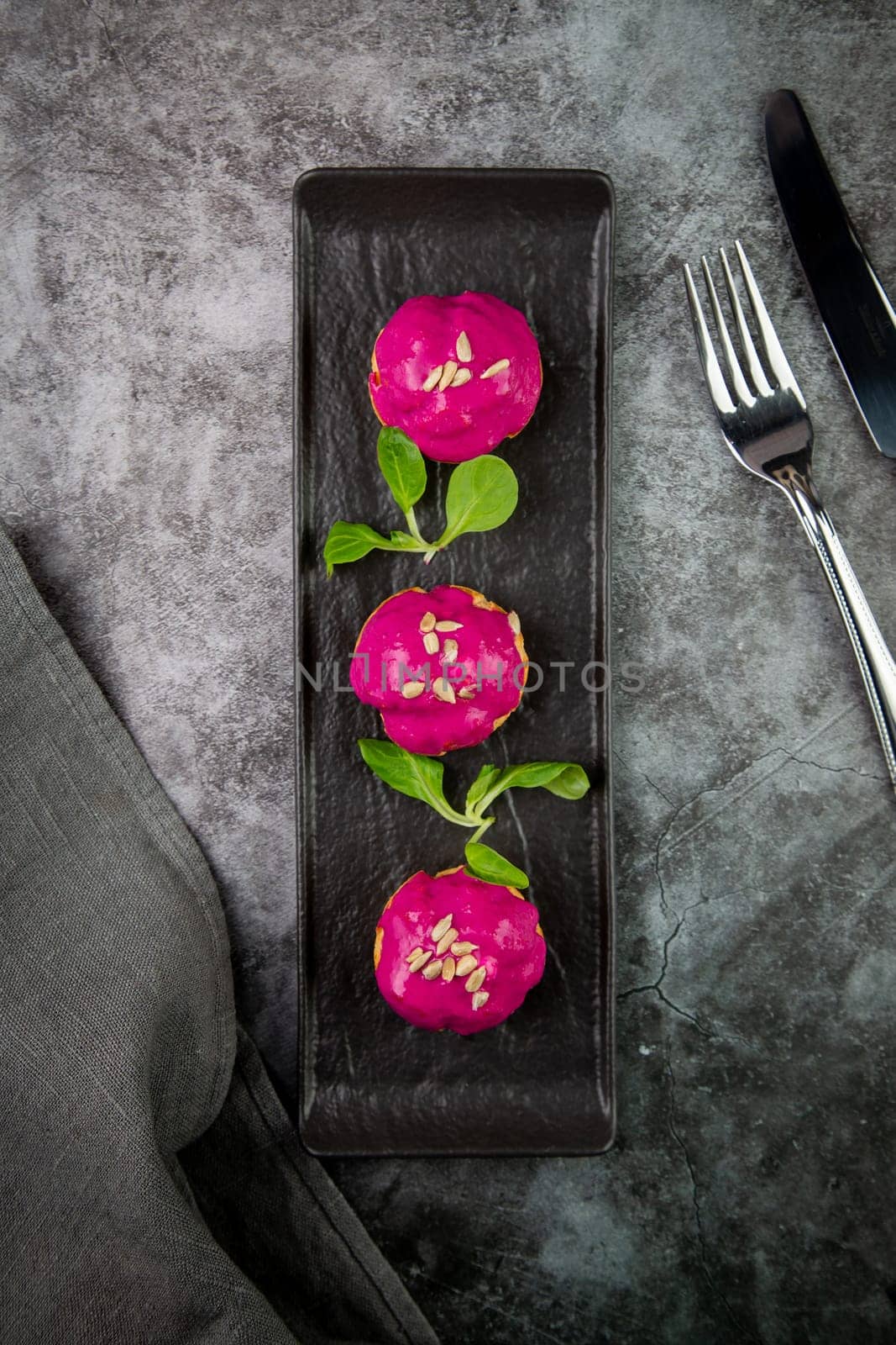 dessert of baked buns with raspberry topping and seed decorations