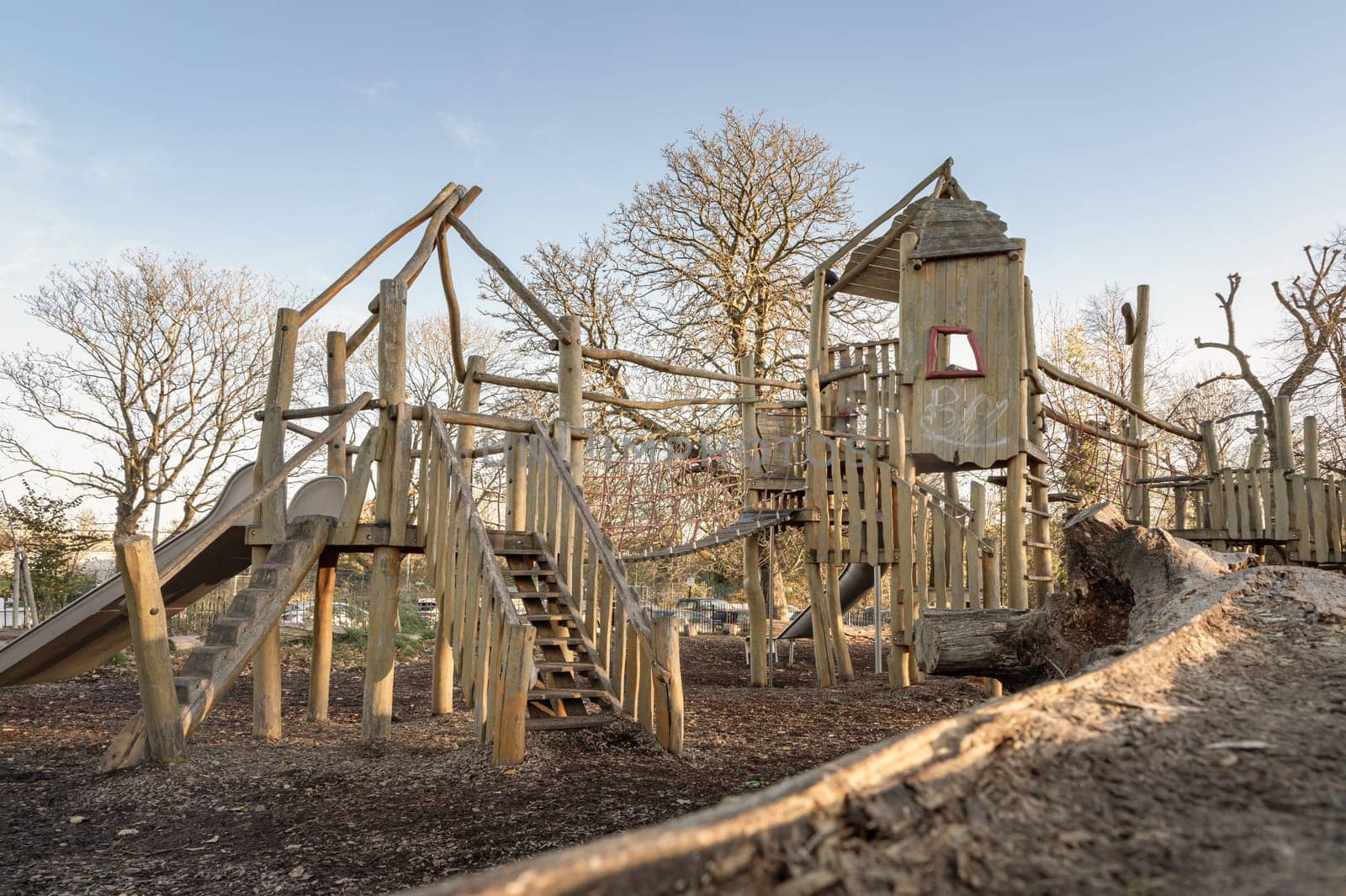 The Children's playground with Slide, Rope Net Bridge made of Wooden Tree trunk in acton park. Empty outdoor playground with wooden equipment for children, Space for text, Selective focus.