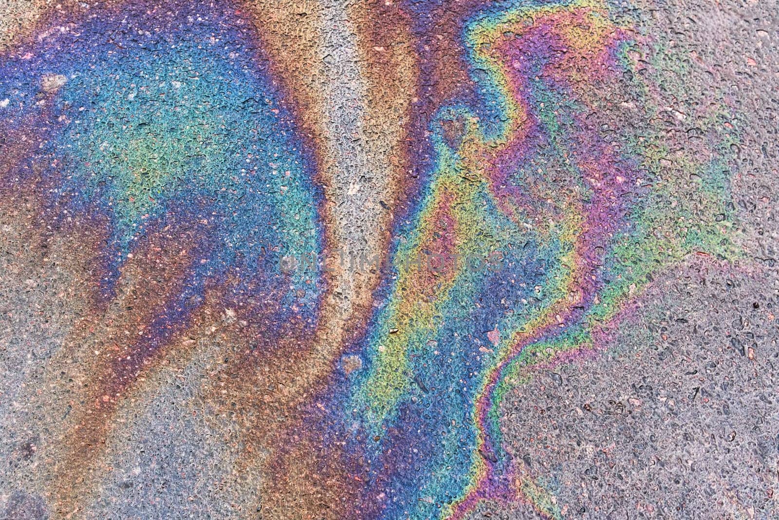 Abstract colored background of leaked gasoline on wet asphalt close-up.