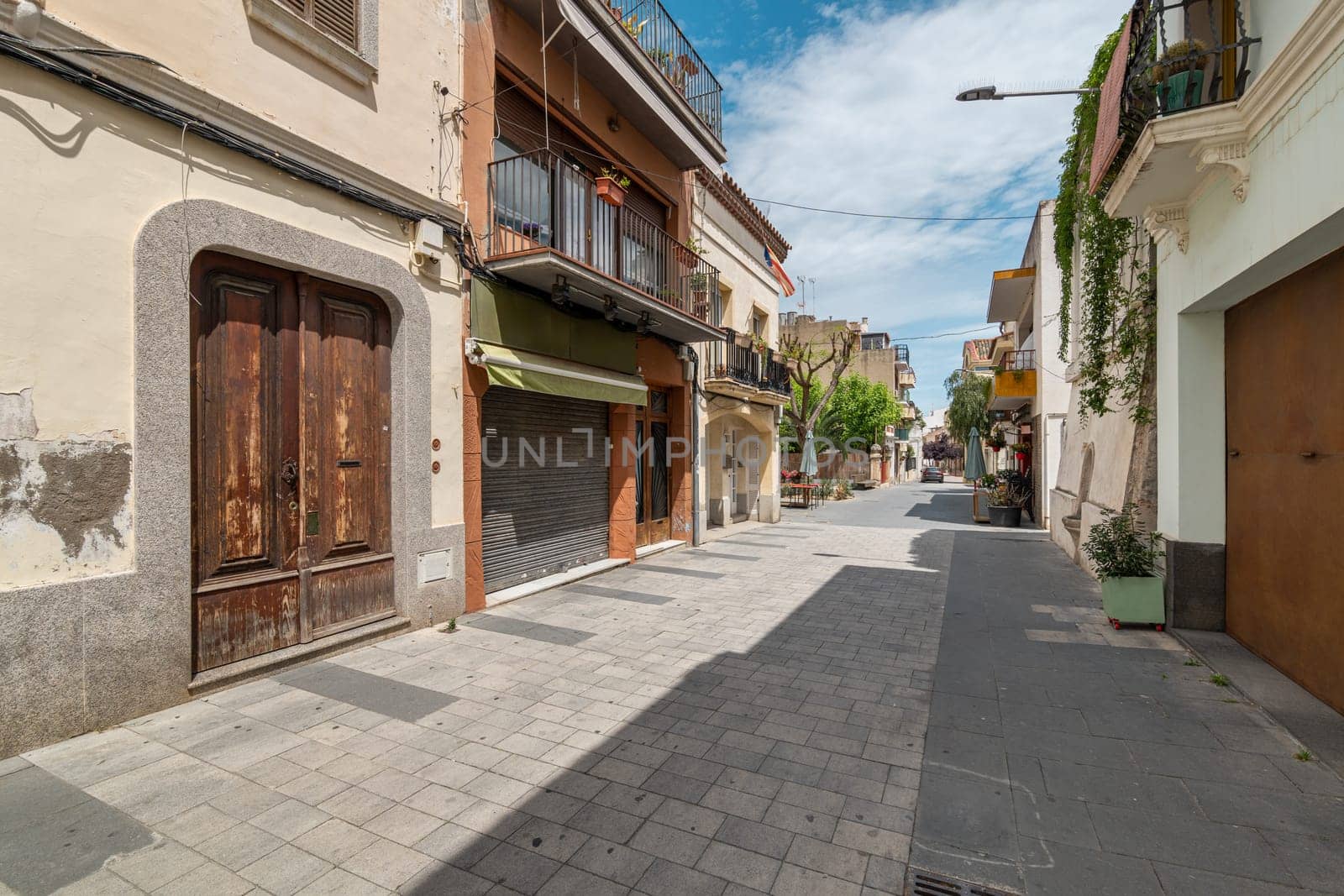 Narrow paved street with old low buildings in Vilassar de Mar town. Historic center architecture of popular Catalonian resort. Travel on holiday