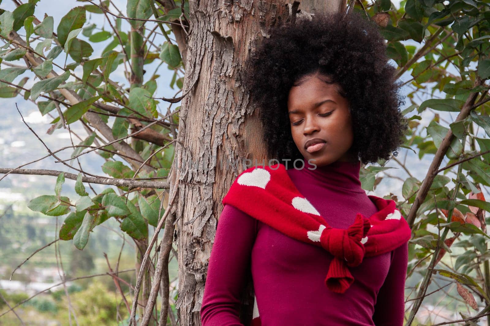 copy space of attractive Afro Ecuadorian woman resting on a tree with her eyes closed with a feeling of peace, harmony and relaxation. Earth day. High quality photo