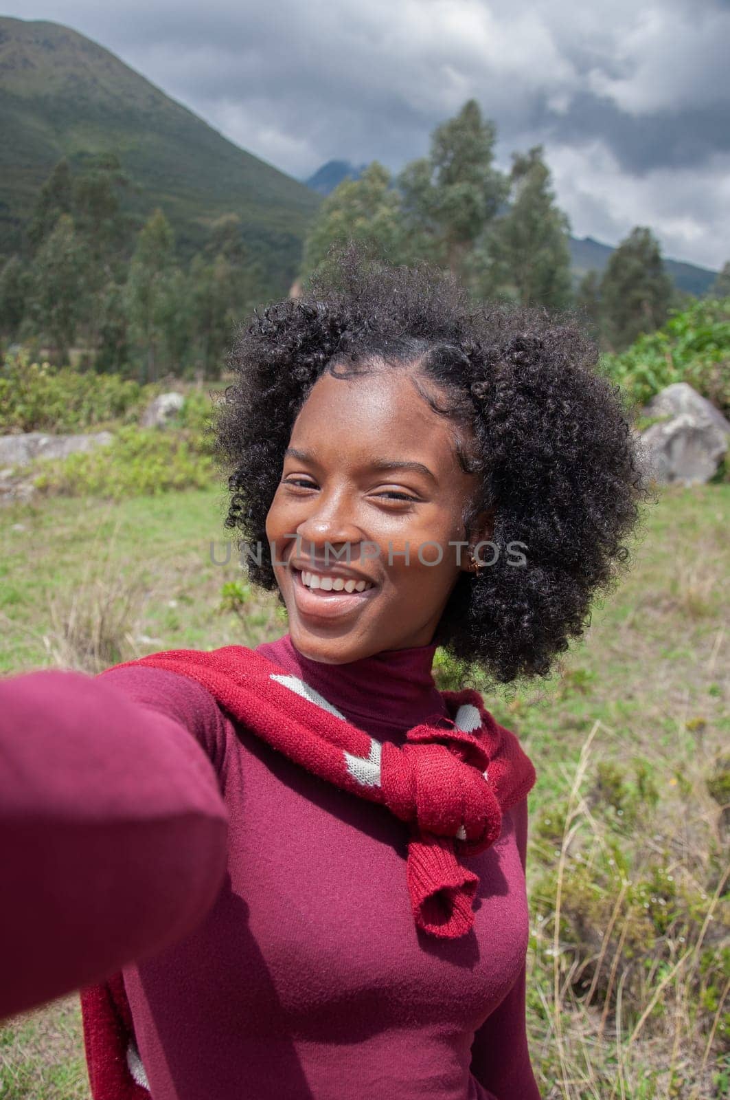 Vertical photo of an Afro girl taking a selfie in a mountain in Ecuador with her cell phone. Earth day. High quality photo