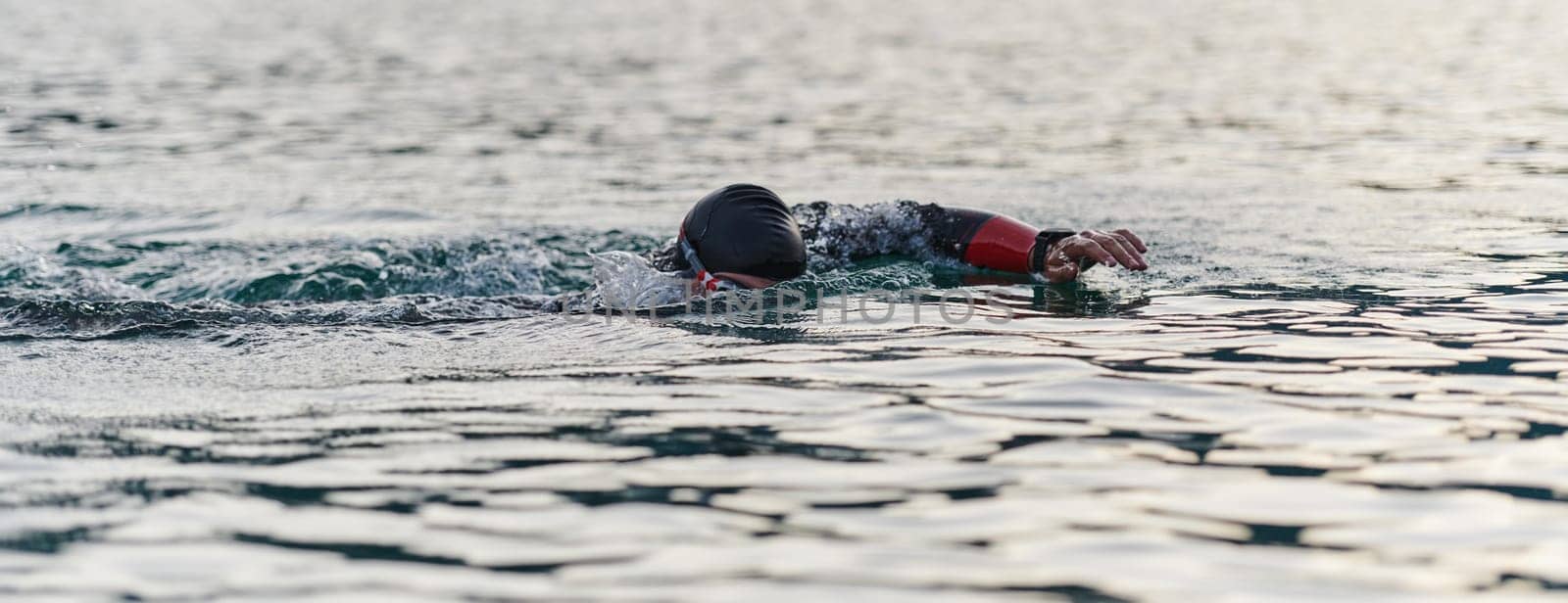 A professional triathlete trains with unwavering dedication for an upcoming competition at a lake, emanating a sense of athleticism and profound commitment to excellence