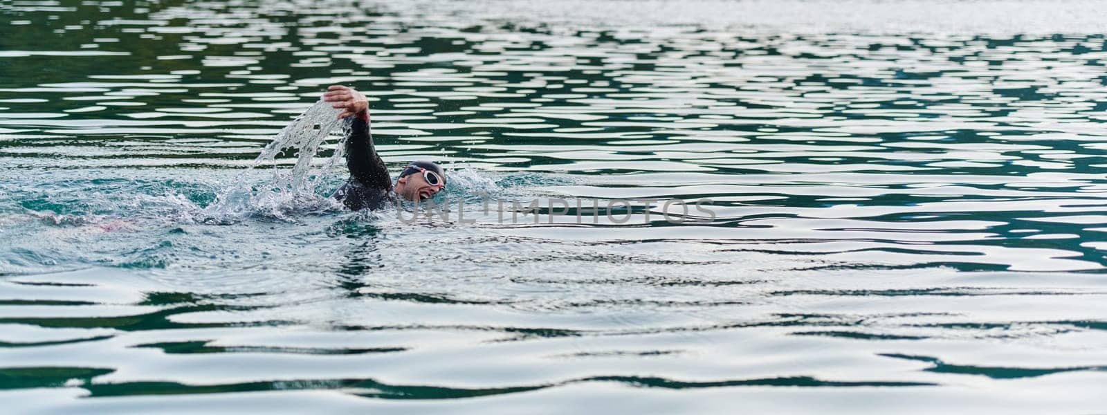 A professional triathlete trains with unwavering dedication for an upcoming competition at a lake, emanating a sense of athleticism and profound commitment to excellence. by dotshock