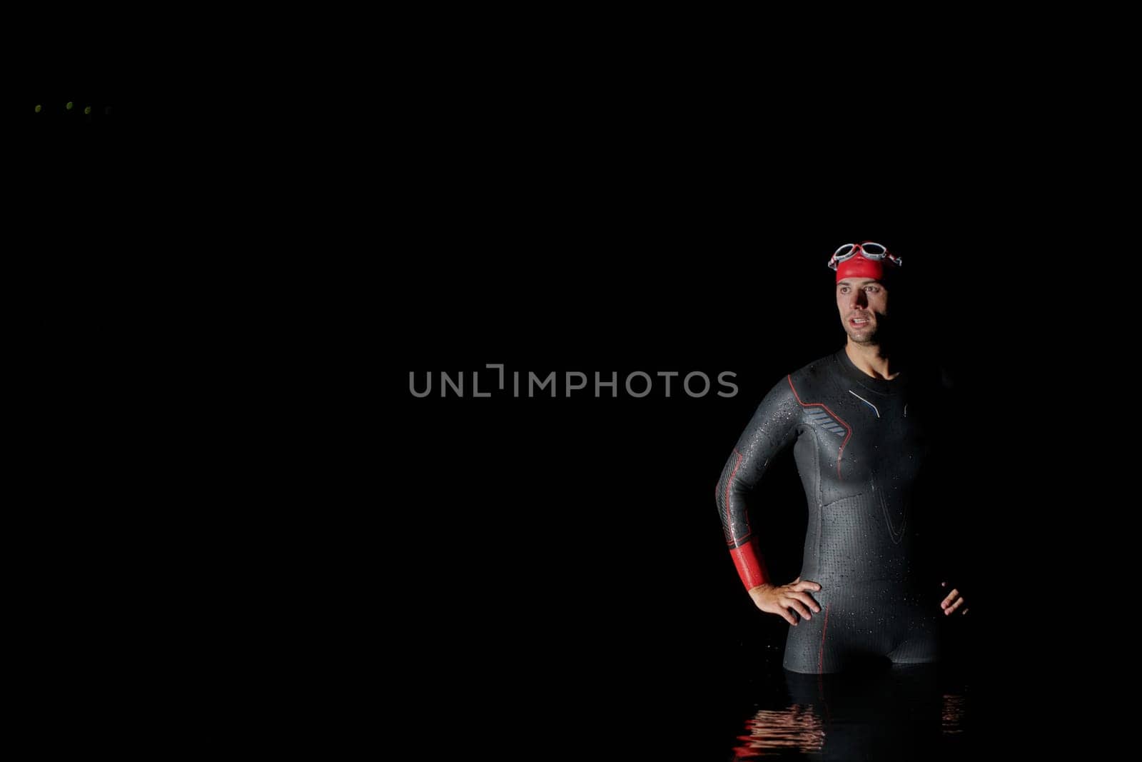 Authentic triathlete swimmer having a break during hard training on night by dotshock