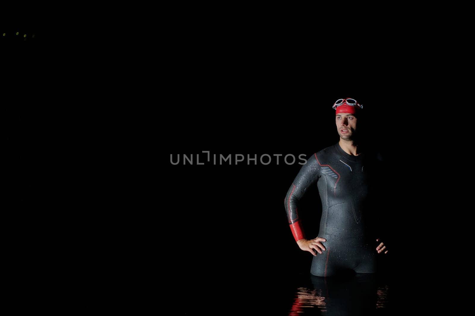 Authentic triathlete swimmer having a break during hard training on night by dotshock