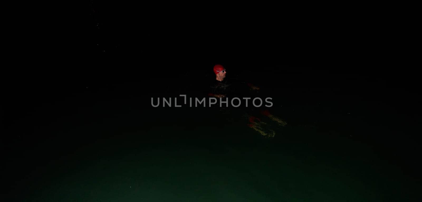 Authentic triathlete swimmer having a break during hard training on night.