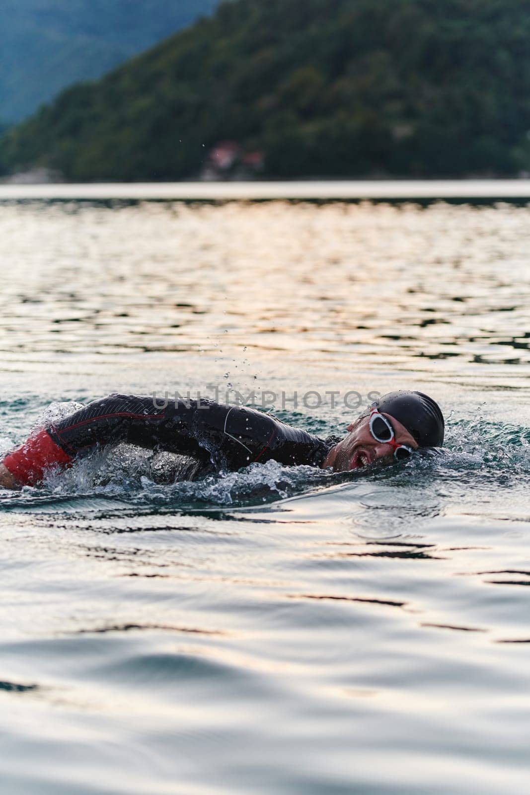 A professional triathlete trains with unwavering dedication for an upcoming competition at a lake, emanating a sense of athleticism and profound commitment to excellence. by dotshock