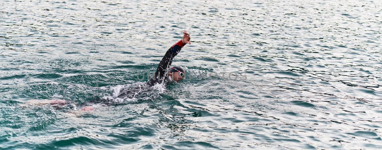 A professional triathlete trains with unwavering dedication for an upcoming competition at a lake, emanating a sense of athleticism and profound commitment to excellence. by dotshock