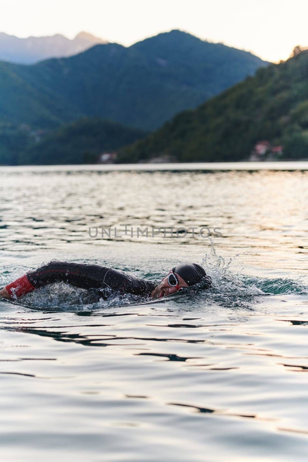 A professional triathlete trains with unwavering dedication for an upcoming competition at a lake, emanating a sense of athleticism and profound commitment to excellence. by dotshock