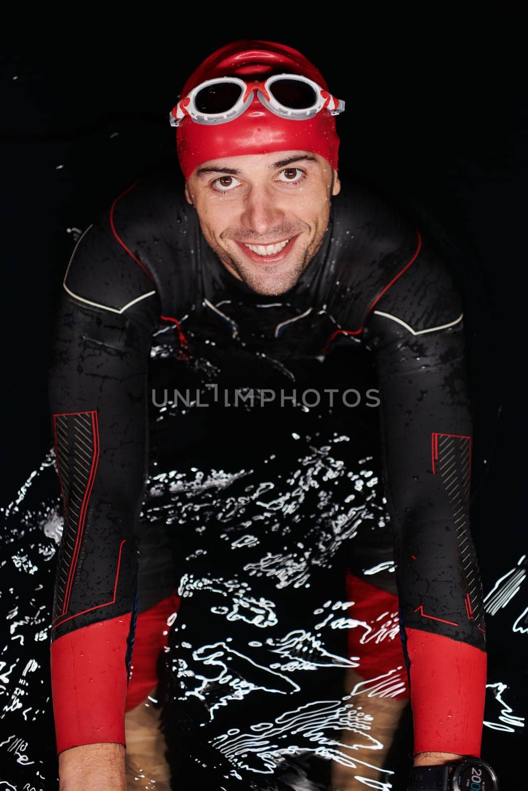 Authentic triathlete swimmer having a break during hard training on night by dotshock