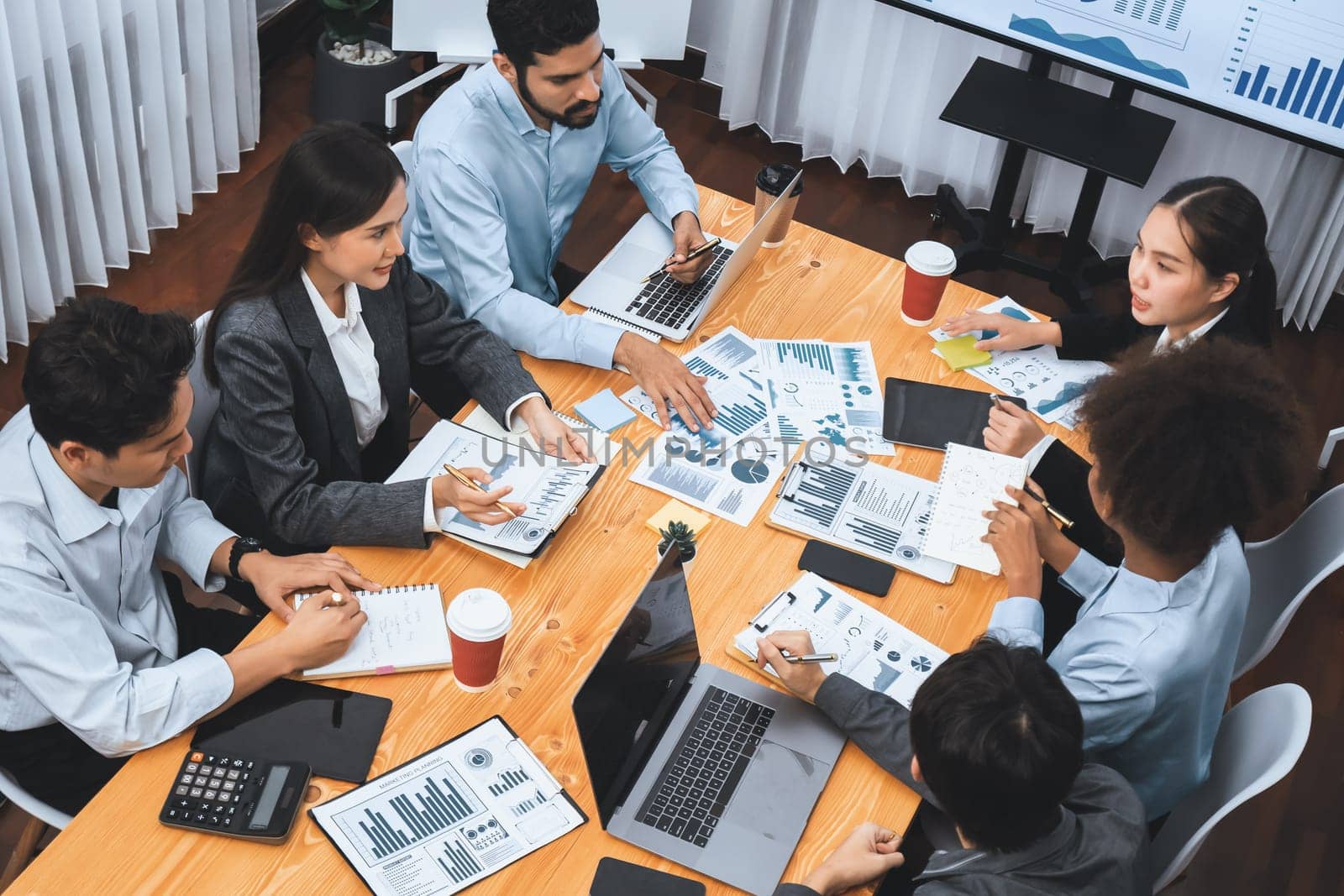 Multiracial analyst team use BI dashboard data to analyze financial report on meeting table. Group of diverse business people utilize data analysis by FIntech for success business marketing. Concord