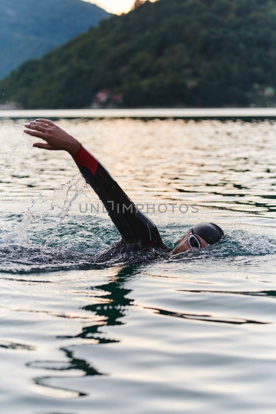 A professional triathlete trains with unwavering dedication for an upcoming competition at a lake, emanating a sense of athleticism and profound commitment to excellence. by dotshock