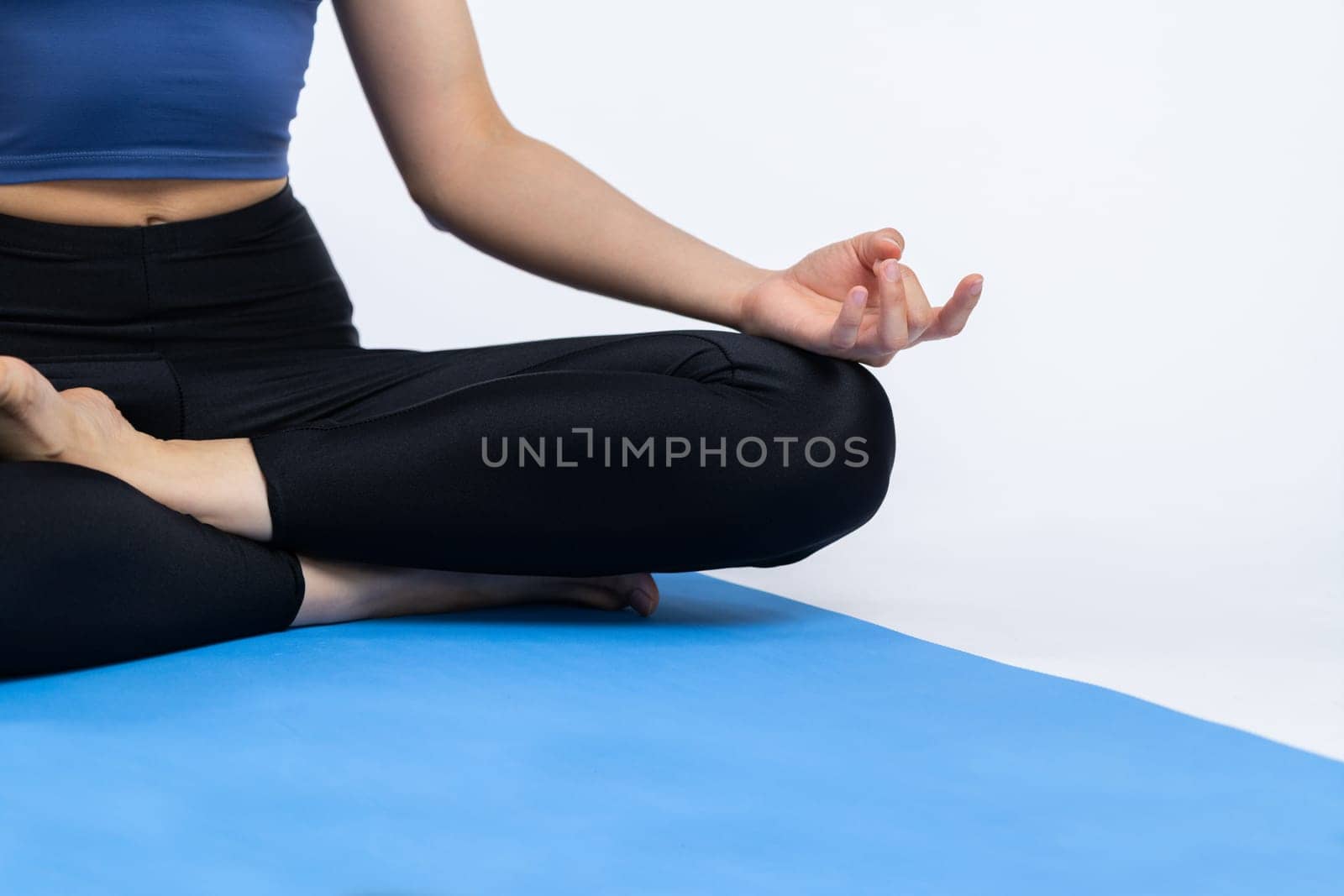 Cropped woman in sportswear doing yoga exercise on fitness mat as her workout training routine. Healthy body care and meditation in yoga lifestyle in studio shot on isolated background. Vigorous