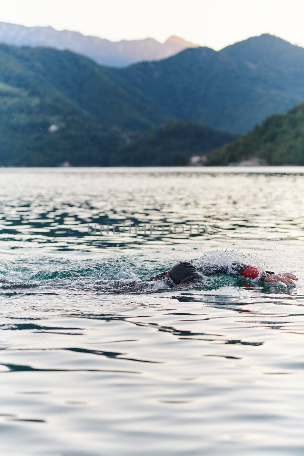 A professional triathlete trains with unwavering dedication for an upcoming competition at a lake, emanating a sense of athleticism and profound commitment to excellence. by dotshock