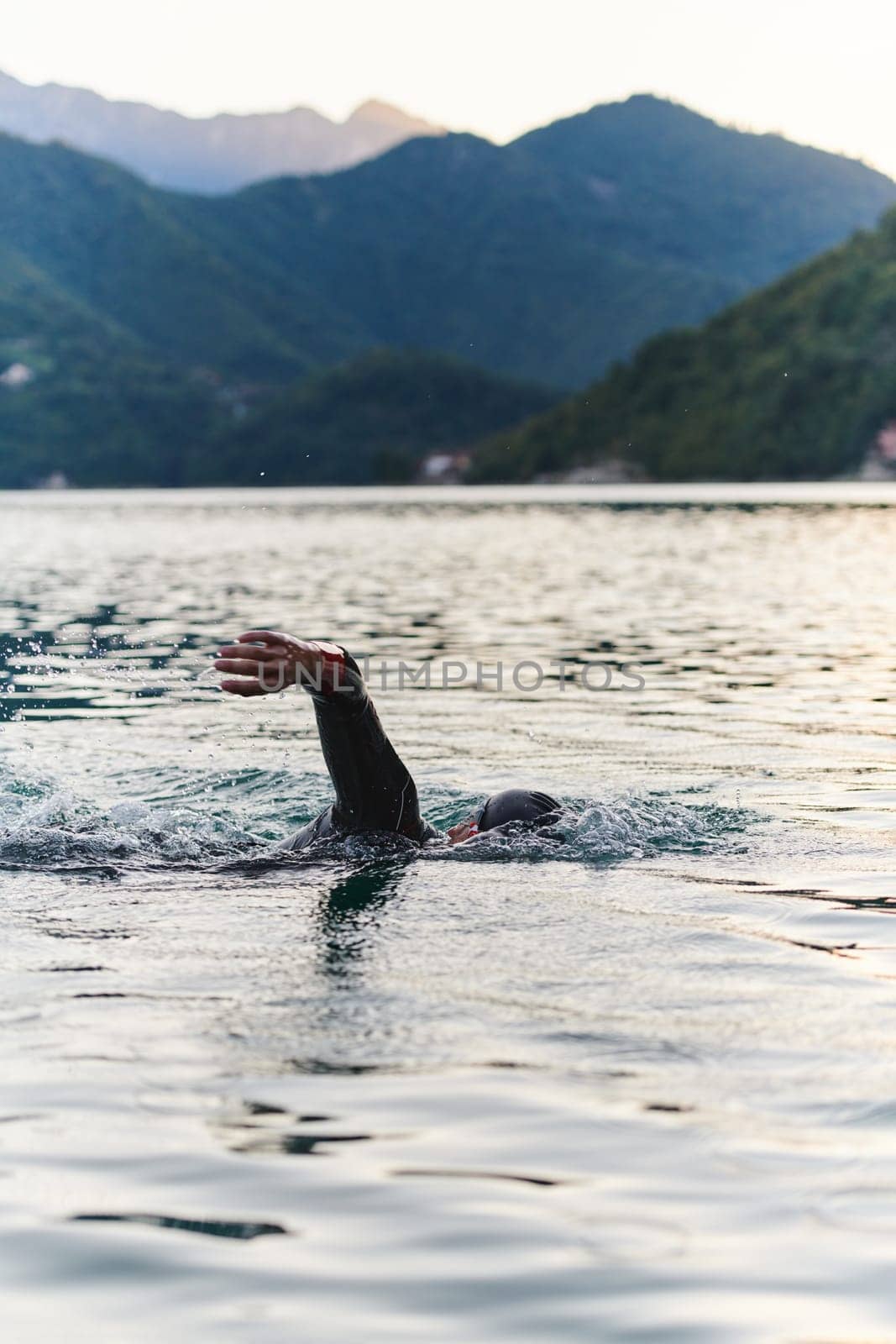 A professional triathlete trains with unwavering dedication for an upcoming competition at a lake, emanating a sense of athleticism and profound commitment to excellence. by dotshock