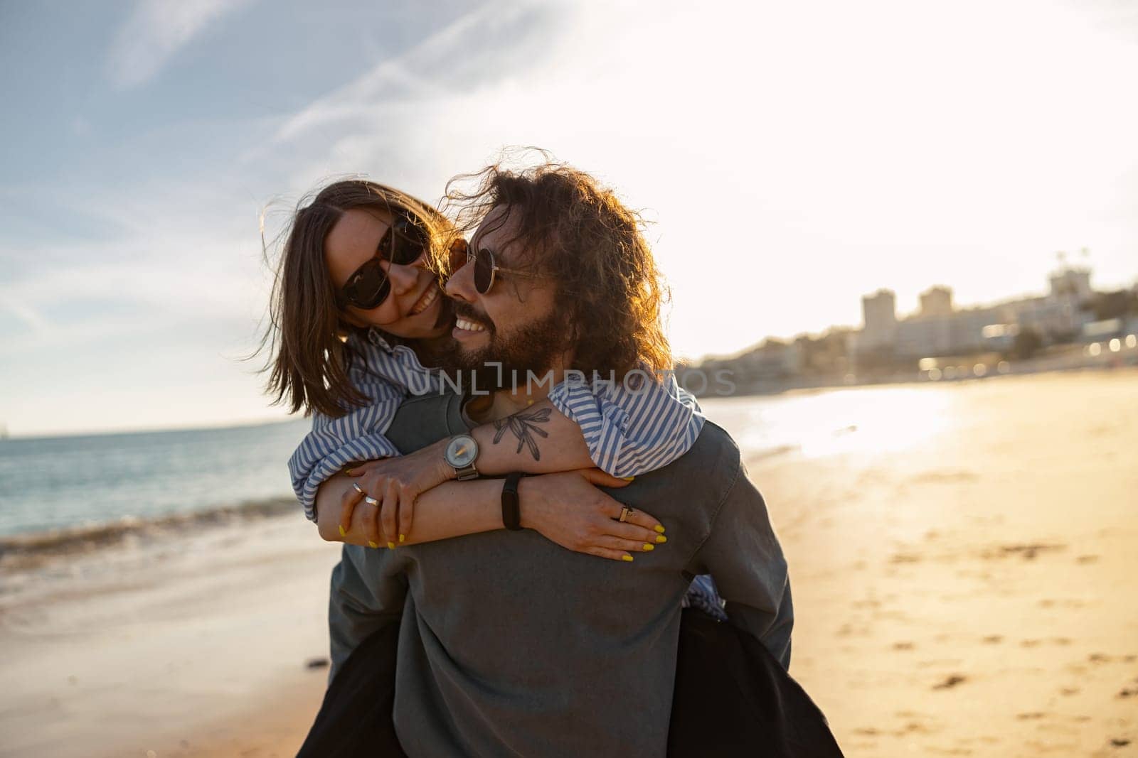 Handsome couple in love hugging while walking along the beach on sunny day. High quality photo
