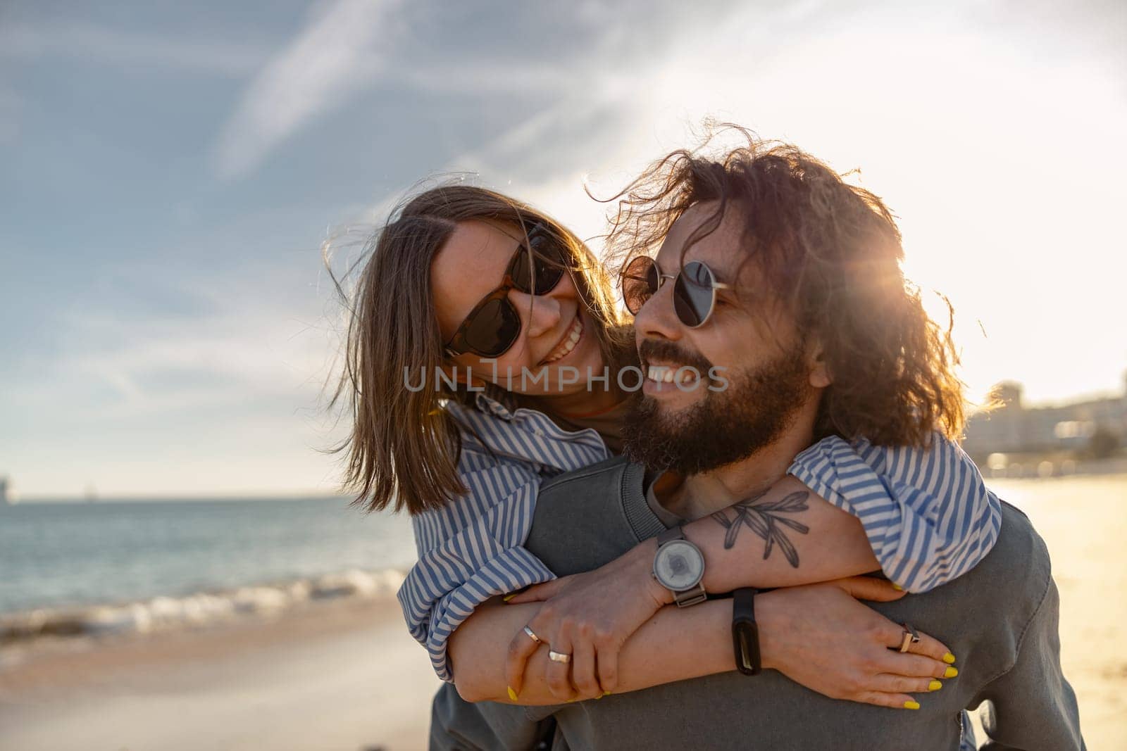 Happy romantic couple in love hugging while walking along the beach on sunny day by Yaroslav_astakhov