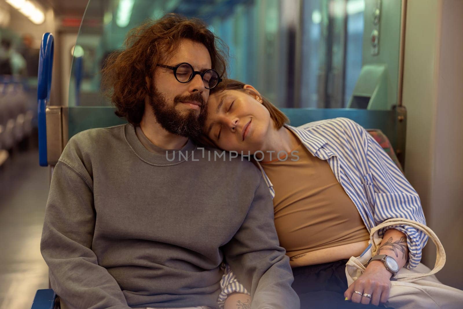 Young tired tourist couple with closed eyes is travel together while riding in public bus by Yaroslav_astakhov
