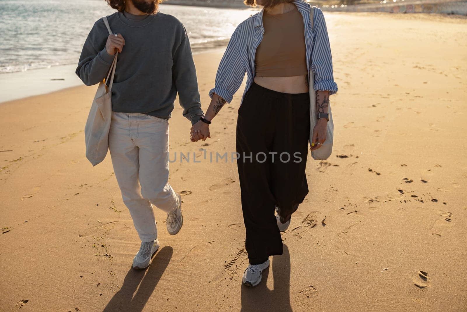 Close up of romantic couple in love is walk holding hands across the sunny beach. High quality photo