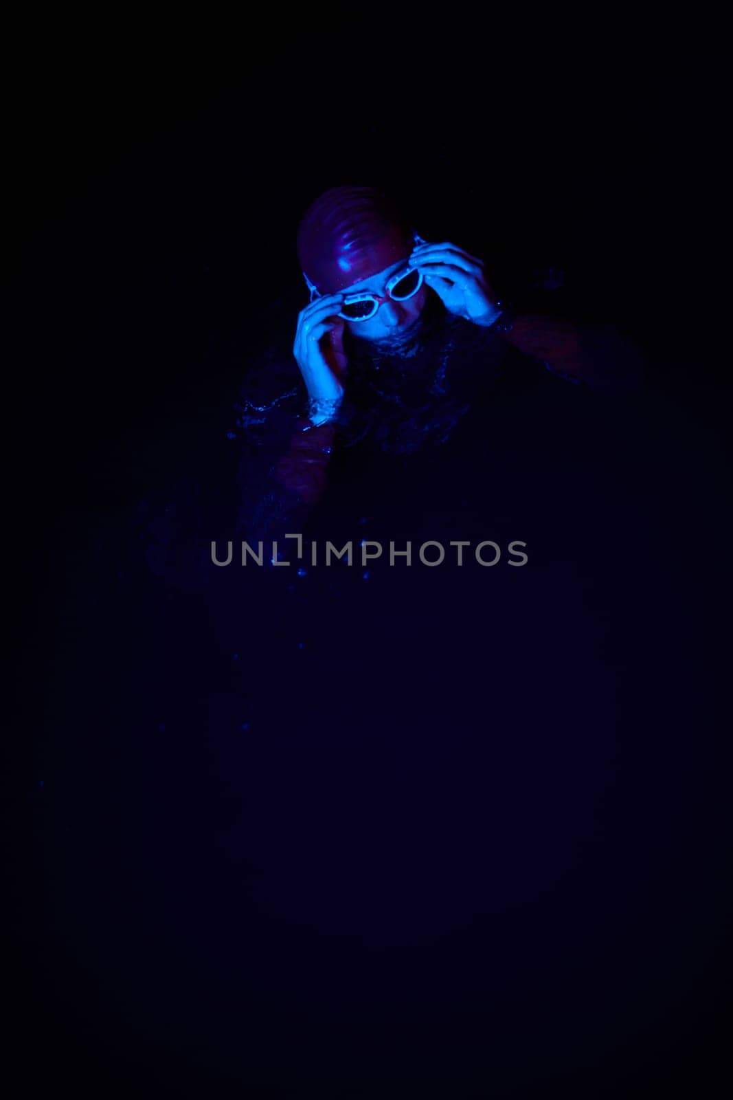 Authentic triathlete swimmer having a break during hard training on night neon gel light by dotshock