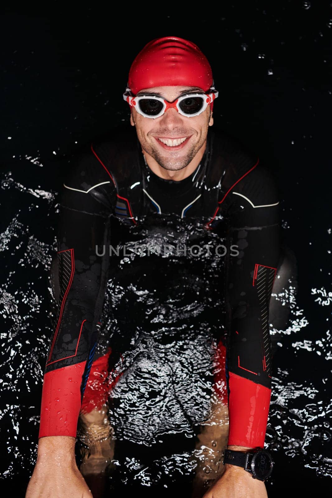 Authentic triathlete swimmer having a break during hard training on night by dotshock