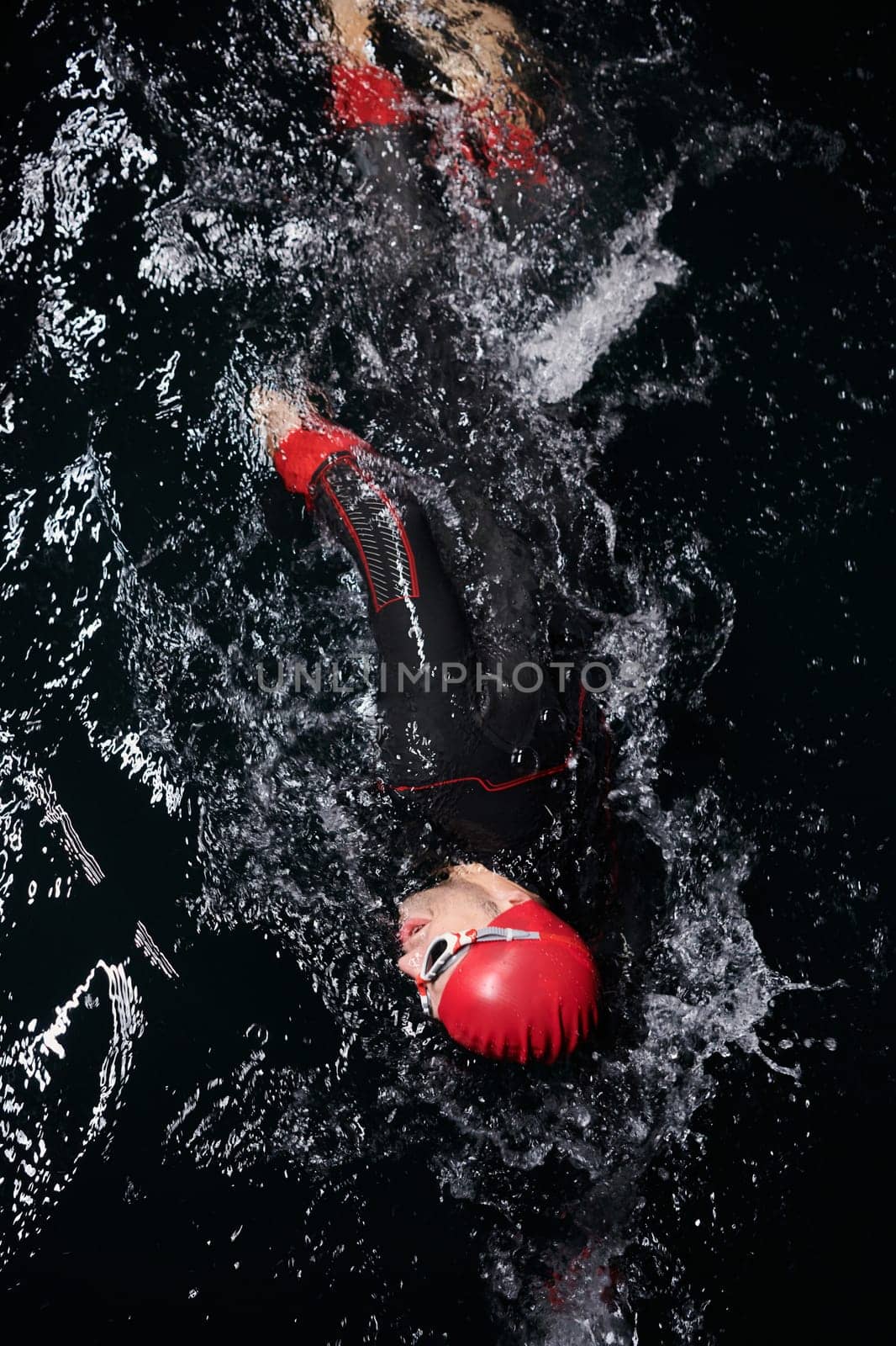 A determined professional triathlete undergoes rigorous night time training in cold waters, showcasing dedication and resilience in preparation for an upcoming triathlon swim competition by dotshock