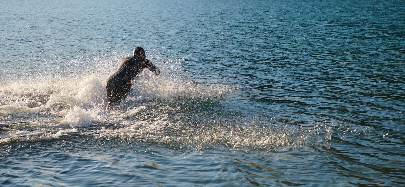 Triathlon athlete starting swimming training on lake.