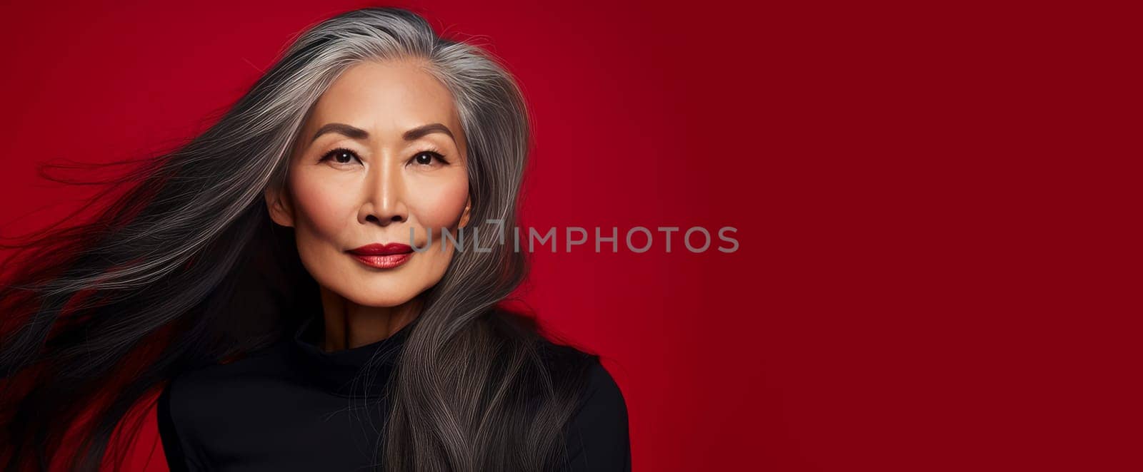 Smiling, elderly, gorgeous Asian woman gray long hair and perfect skin, on a red background, banner. Advertising of cosmetic products, spa treatments, shampoos and hair care products, dentistry and medicine, perfumes and cosmetology for senior women