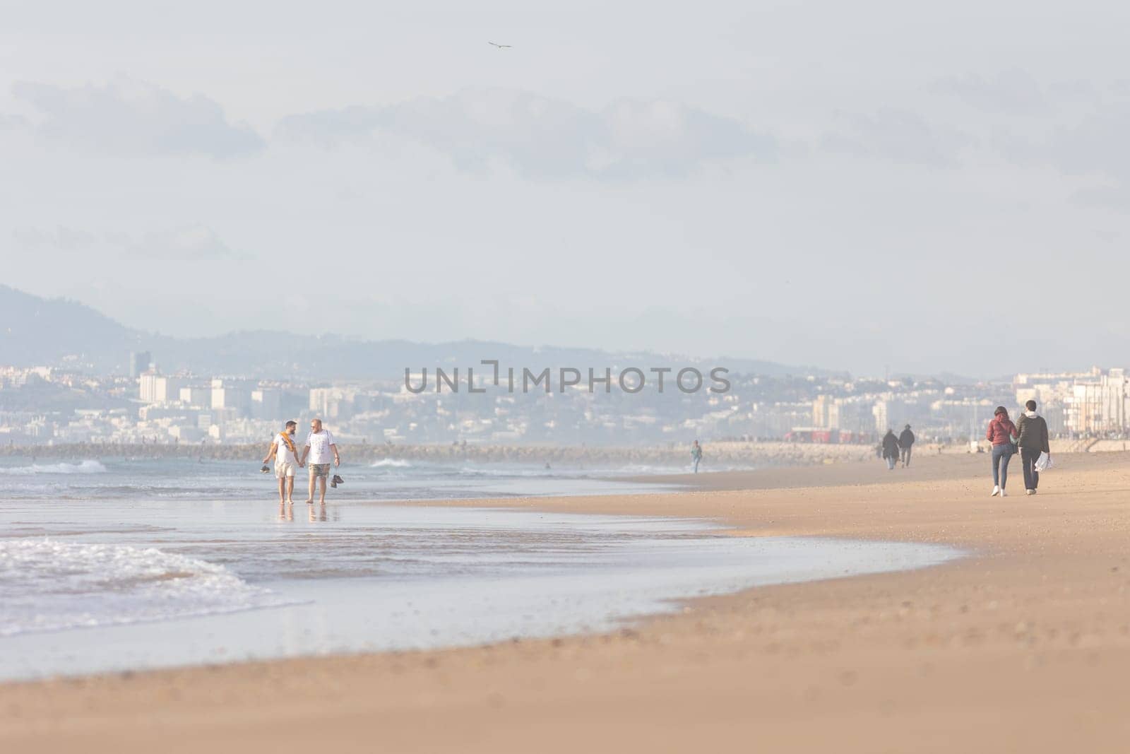25 november 2023, Lisbon, Portugal - loving couple of men Walking Along Beach next to the ocean