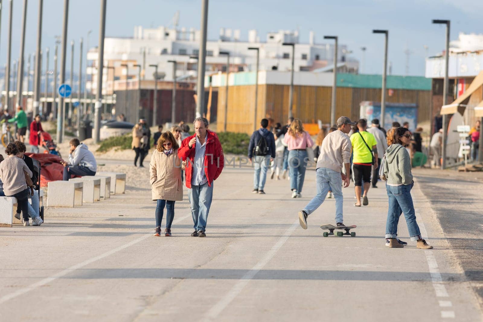 25 november 2023, Lisbon, Portugal - People walking on promenade near ocean - telephoto