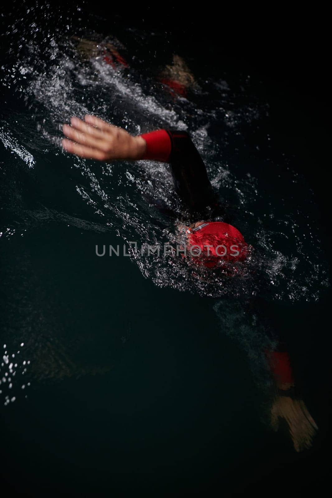 A determined professional triathlete undergoes rigorous night time training in cold waters, showcasing dedication and resilience in preparation for an upcoming triathlon swim competition by dotshock